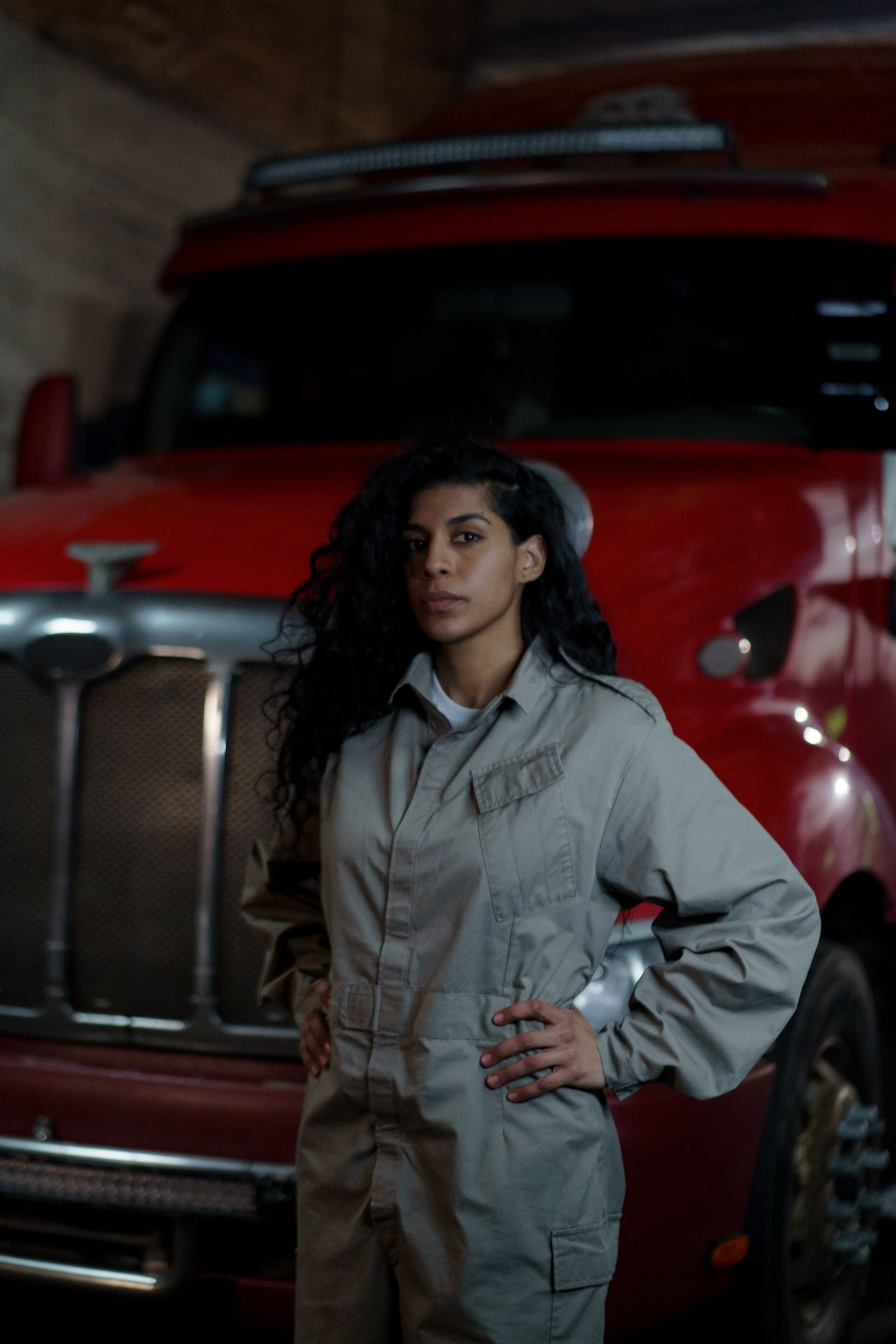 A driver in uniform standing in front of her red Peterbilt