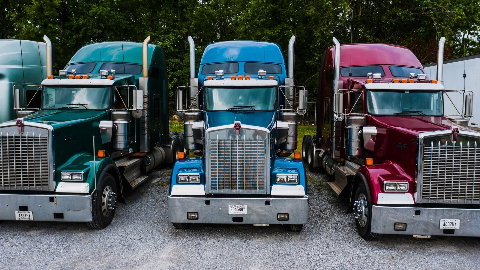 Three Kenworth tractors lined up in a fleet yard